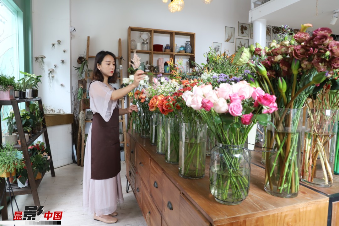 王黎媛是一名河南姑娘，在昆明念完大學(xué)后，就再也舍不下春城的藍(lán)天陽光、青山碧水，更舍不下這里的四時繁花，于是就干脆留了下來，成了一名媒體人。2017年的時候又毅然辭去工作，創(chuàng)業(yè)開起了花店，成了都市里的一名“花房姑娘”。圖為王黎媛在自己的花店中整理鮮花。新華網(wǎng) 周亞平/攝 念新洪/文